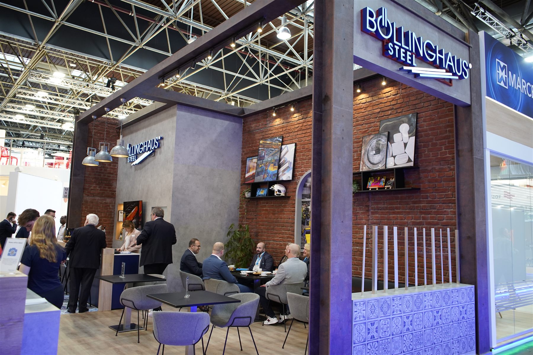 Böllinghaus Steel Messestand mit Backsteinwand, Loungebereich und warmem Messinglicht